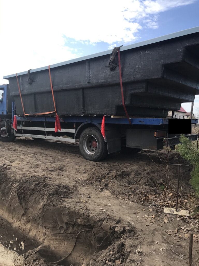 Доставка чаши композитного бассейна на грузовом автомобиле к краю котлована на объекте в городе Днепр.