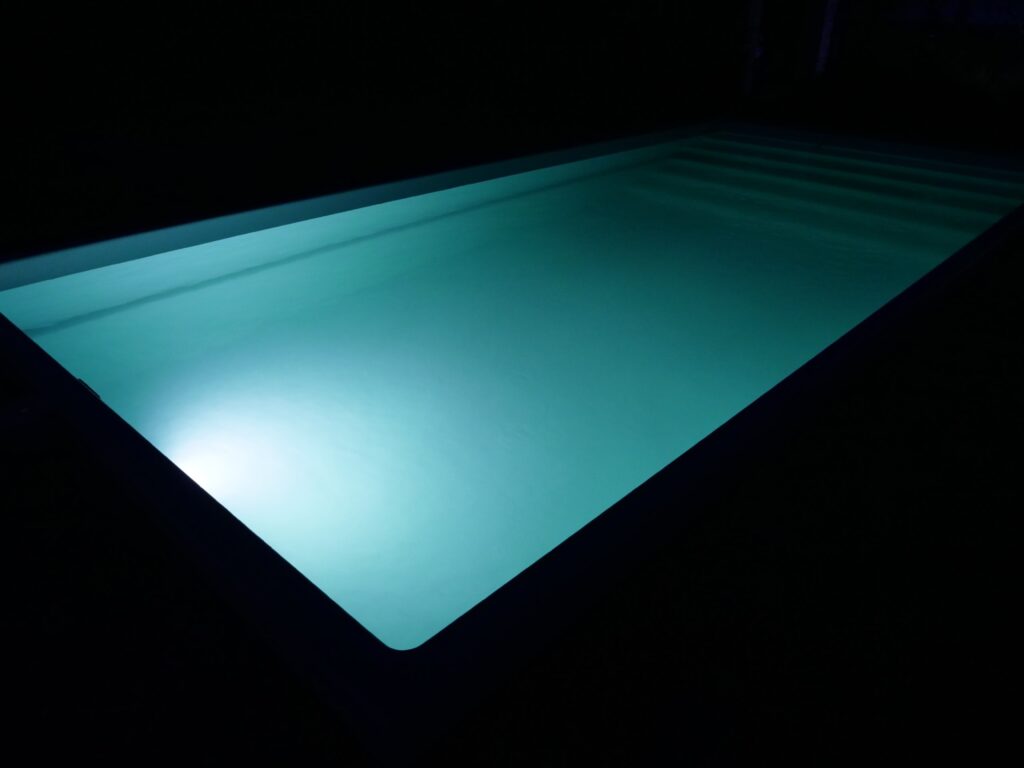 Бирюзовая подводная LED-подсветка композитного бассейна Эклипс в ночное время.