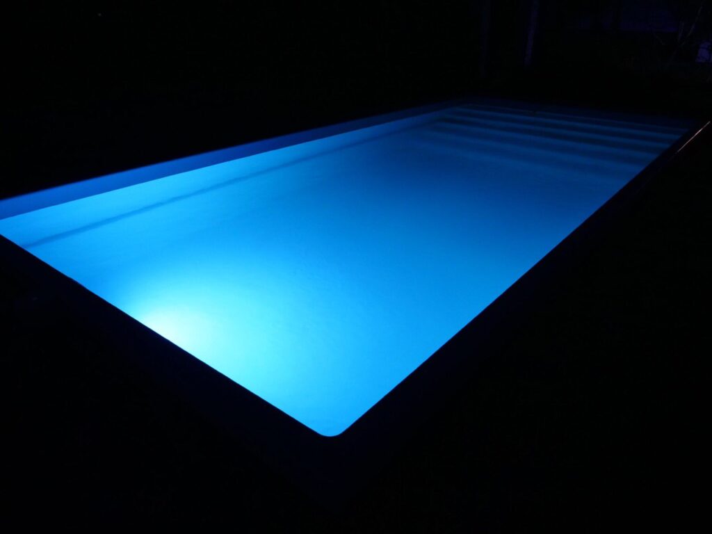 Классическая синяя LED-подсветка воды в композитном бассейне в ночное время.
