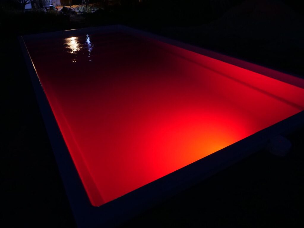 Яркая красная LED-подсветка воды в композитном бассейне в ночное время