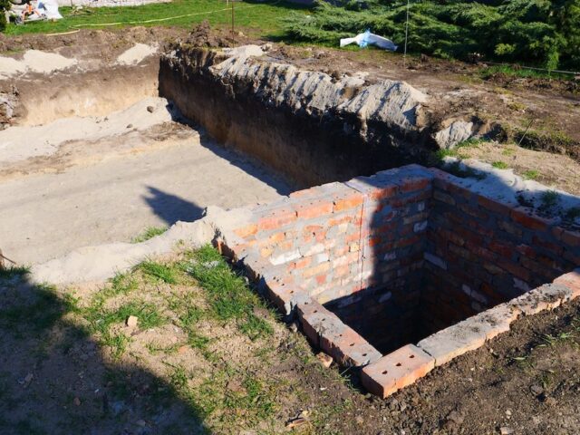 Крупный план котлована с песчаной подушкой и кирпичного технического помещения для фильтрационного оборудования бассейна — Grand Pools.