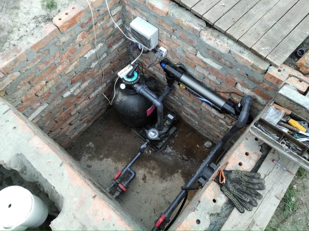 Обладнання для очищення води в басейні: піщаний фільтр, насос та ультрафіолетова лампа всередині цегляного технічного приямка.