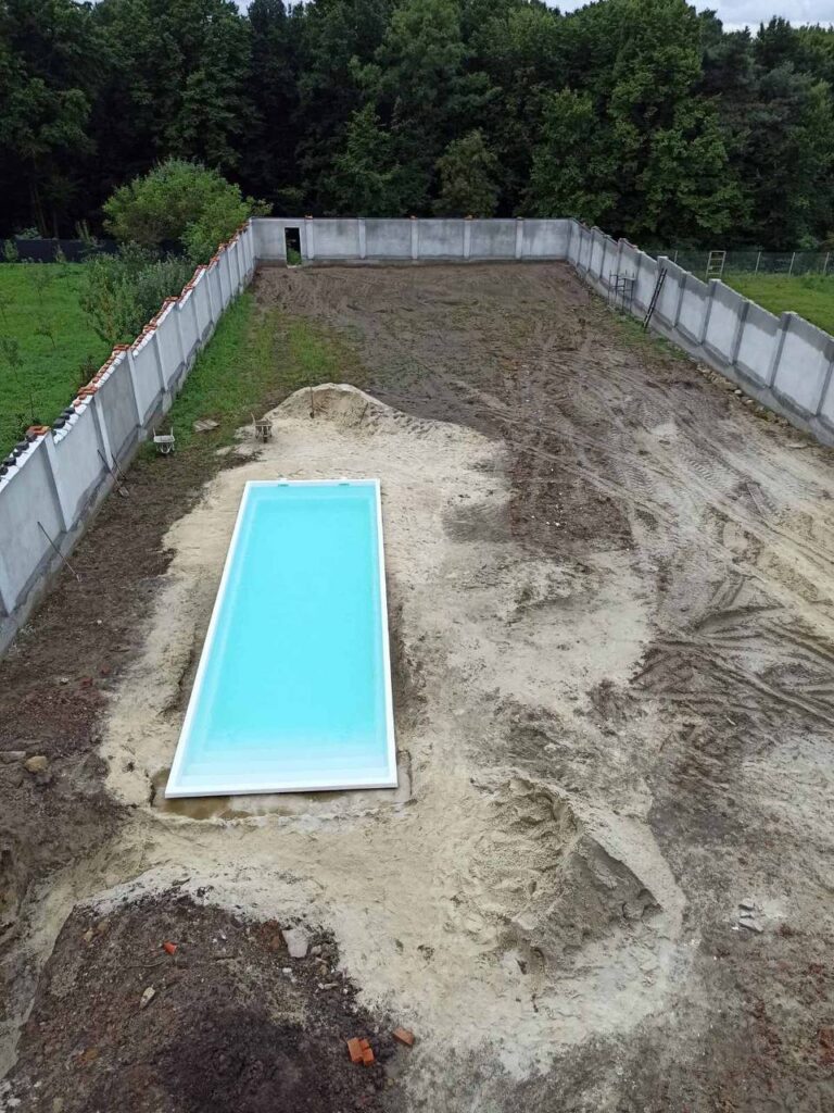Большая чаша композитного бассейна Эклипс 11 метров с водой на этапе строительства и засыпки котлована