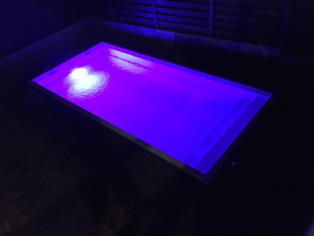 Ночной композитный бассейн с интенсивной фиолетовой LED-подсветкой чаши и ступеней