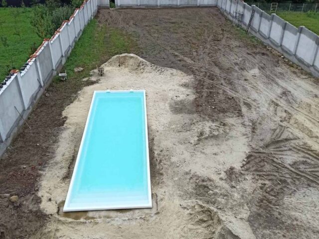 Велика чаша композитного басейну Екліпс 11 метрів з водою на етапі будівництва та засипки котловану
