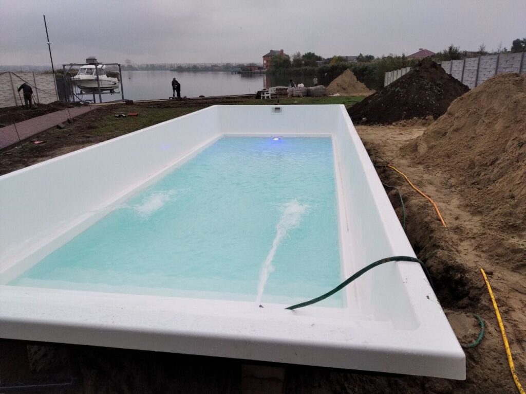Процес наповнення білого композитного басейну Екліпс 10 метрів водою з увімкненим синім підсвічуванням