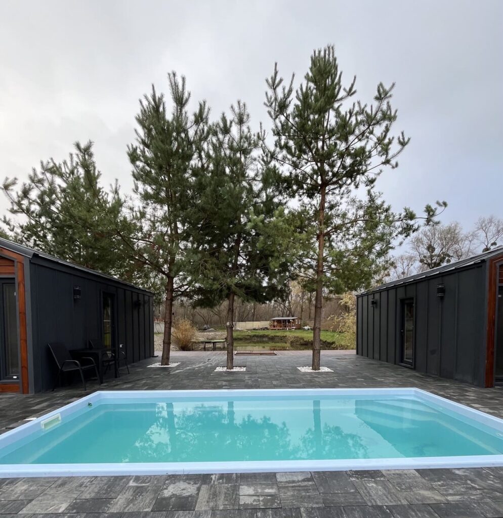 Прямоугольный светло-синий композитный бассейн Luna 6 метров от Grand Pools, установленный между двумя современными домами