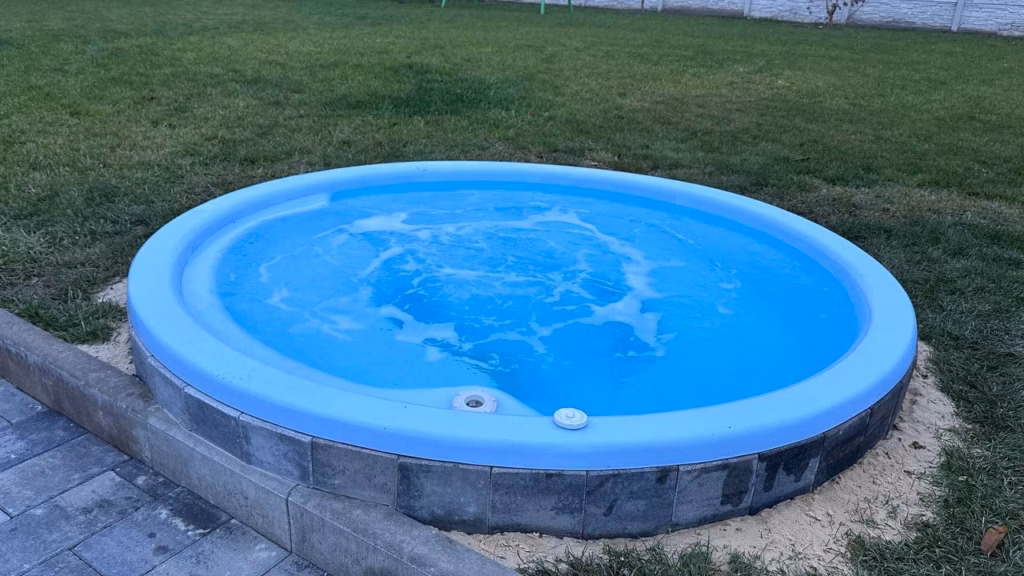 Синя вулична купель з гідромасажем на фоні газону.