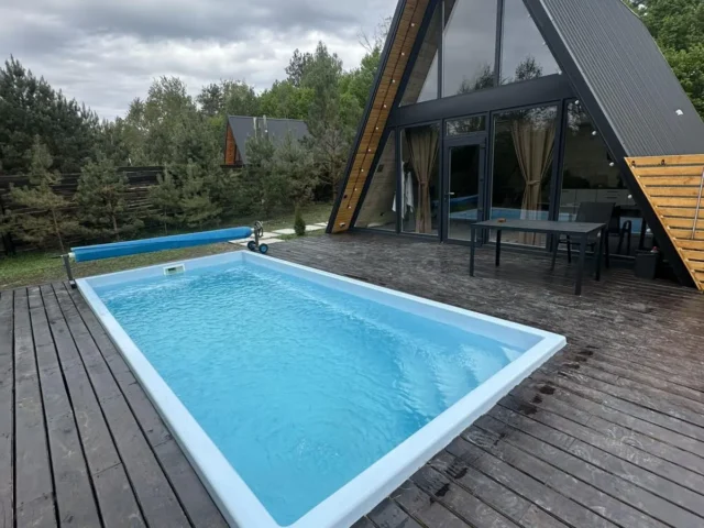 Композитный бассейн Luna 6 метров на деревянной террасе у дома в стиле А-фрейм.