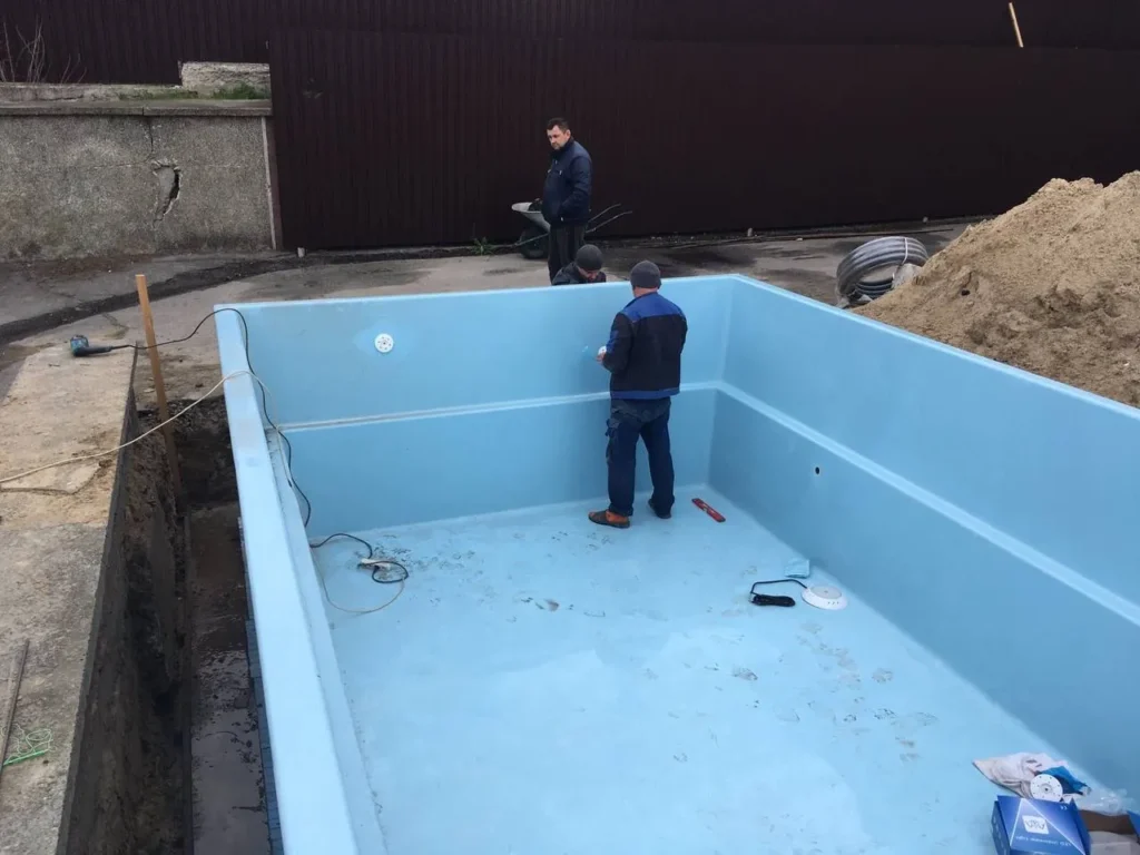 Монтажники внутри чаши бассейна во время установки.